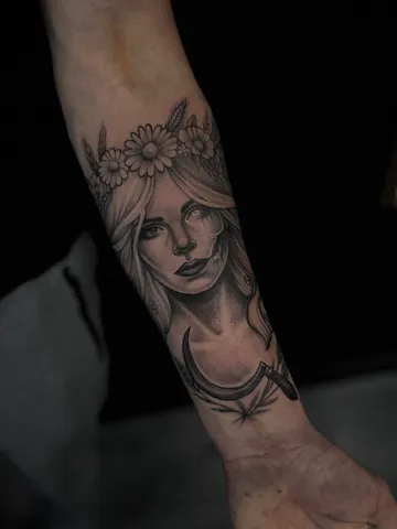 Portret kobiety w wianku z księżycem, czarno-szary tatuaż na przedramieniu.
